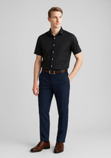 A man stands wearing a black shirt and navy slimline pants, complemented by a brown belt and shoes. A man stands wearing a black shirt and navy slimline pants, complemented by a brown belt and shoes.