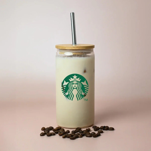 A drink bottle with a wooden lid and metal straw, featuring a logo, surrounded by coffee beans. A drink bottle with a wooden lid and metal straw, featuring a logo, surrounded by coffee beans.