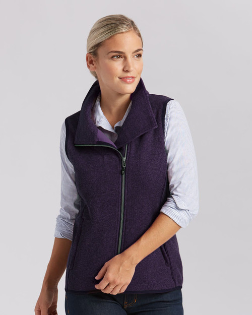 A purple ladies vest featuring a high collar and front zip, worn over a striped shirt. Includes a logo. A purple ladies vest featuring a high collar and front zip, worn over a striped shirt. Includes a logo.