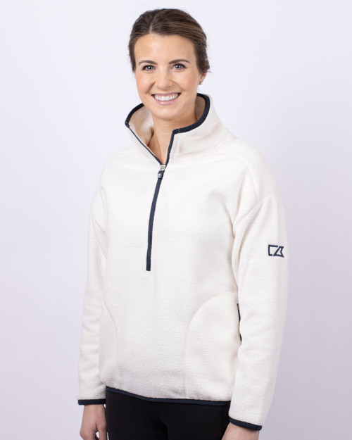 A white eco sherpa half zip jacket with a navy zipper and a logo on the sleeve, worn by a smiling person. A white eco sherpa half zip jacket with a navy zipper and a logo on the sleeve, worn by a smiling person.