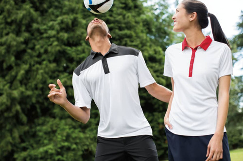 A man and woman wearing a white polo shirt with black details and a white polo shirt with a red collar, respectively. A man and woman wearing a white polo shirt with black details and a white polo shirt with a red collar, respectively.
