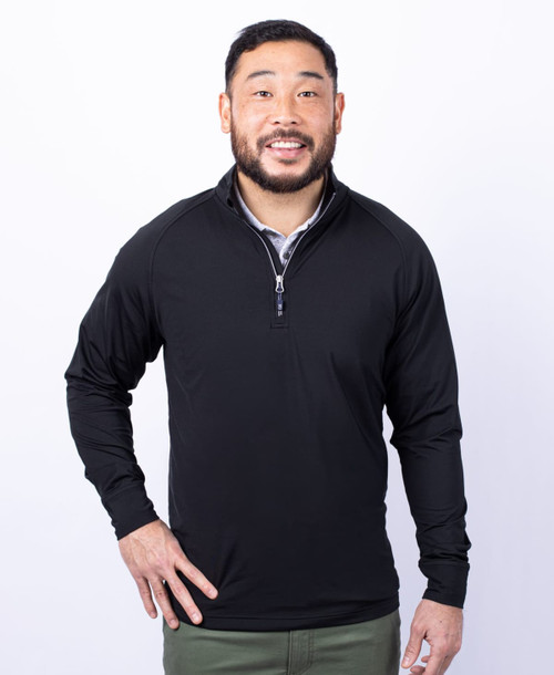 A man wearing a black half zip jumper with a collar and a logo on the chest. A man wearing a black half zip jumper with a collar and a logo on the chest.