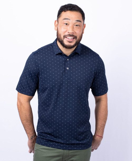 A man is wearing a men's navy polo shirt with a tile print pattern and a logo on the chest. A man is wearing a men's navy polo shirt with a tile print pattern and a logo on the chest.