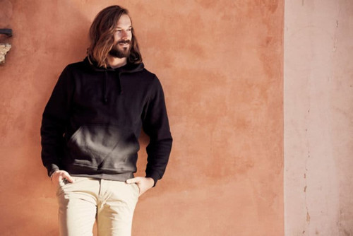 A black Stockholm hoodie displayed on a model against a warm-toned wall, featuring a front pocket and drawstring hood. A black Stockholm hoodie displayed on a model against a warm-toned wall, featuring a front pocket and drawstring hood.