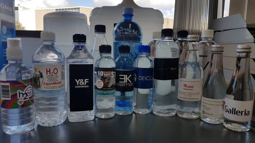 A collection of various plastic water bottles, including a 350ml custom bottled water, featuring multiple colours and branding.
