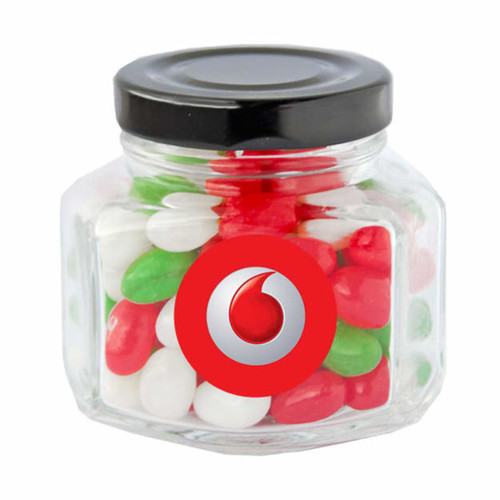 A clear glass jar with a black screw top filled with red, green, and white jelly beans. It has a logo on the front. A clear glass jar with a black screw top filled with red, green, and white jelly beans. It has a logo on the front.