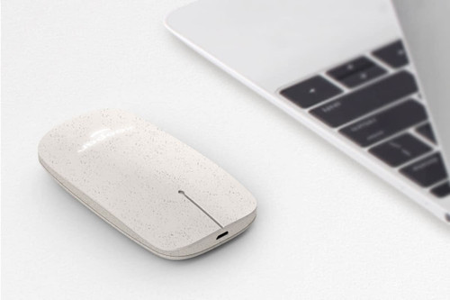 A biodegradable wireless mouse in a speckled light grey colour, positioned beside a silver laptop. A biodegradable wireless mouse in a speckled light grey colour, positioned beside a silver laptop.