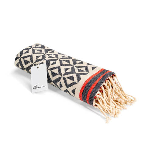 A rolled beach towel featuring a geometric pattern in black, cream, and red, complete with tassels and a tag. A rolled beach towel featuring a geometric pattern in black, cream, and red, complete with tassels and a tag.