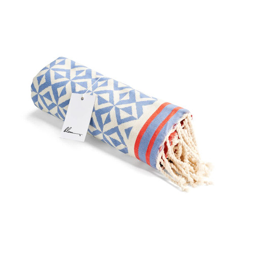 A rolled blue and white patterned beach towel with tassels and a tag. A rolled blue and white patterned beach towel with tassels and a tag.