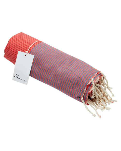 A rolled beach towel in red and pink stripes, featuring a fringed edge and a tag attached.