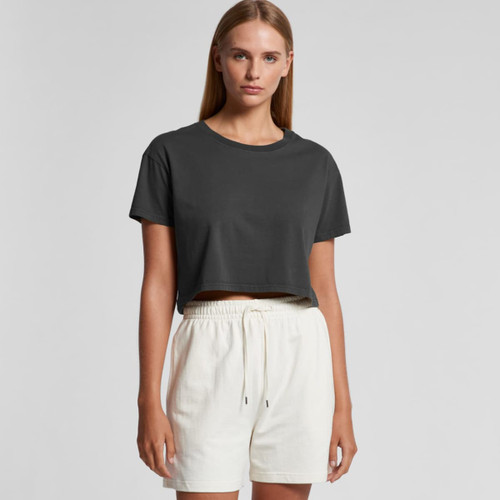A cropped black T-shirt is paired with white shorts. The model stands against a neutral background. A cropped black T-shirt is paired with white shorts. The model stands against a neutral background.