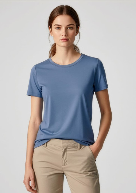 A women's short sleeve tee in blue, made from a smooth fabric, paired with light-coloured pants. The shirt features a logo.