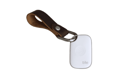 A Tile Pro tracking device in white attached to a genuine leather key fob in brown. A Tile Pro tracking device in white attached to a genuine leather key fob in brown.