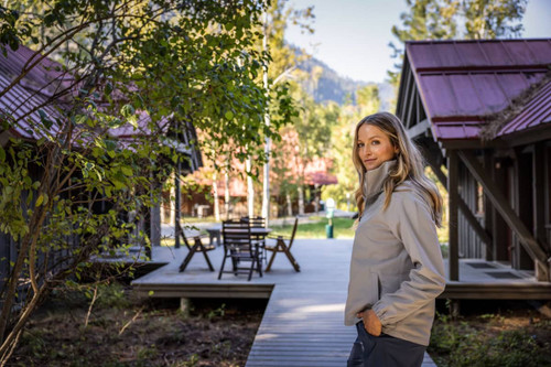 A light grey ladies full zip jacket is worn by a woman standing outdoors, surrounded by cabins and greenery. A light grey ladies full zip jacket is worn by a woman standing outdoors, surrounded by cabins and greenery.