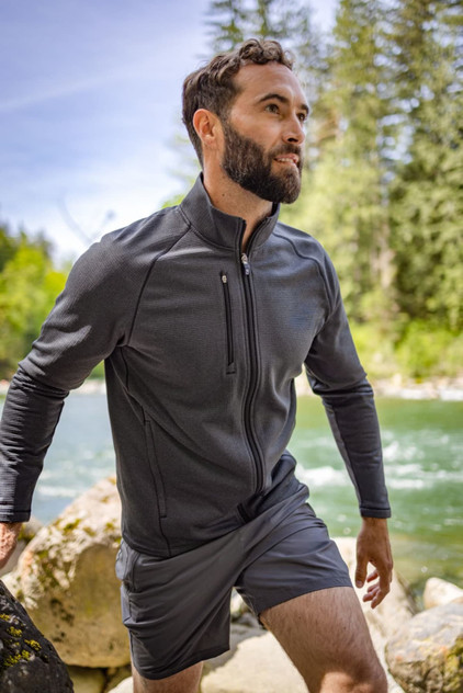 Men’s Peshastin Eco Fleece full zip jacket in dark grey, featuring a front zip pocket, set against a natural river backdrop. Men’s Peshastin Eco Fleece full zip jacket in dark grey, featuring a front zip pocket, set against a natural river backdrop.