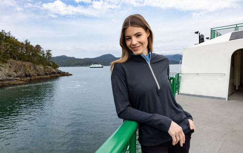 A half-zip hoodie in navy blue worn by a woman, featuring long sleeves and a subtle logo, against a scenic waterfront background. A half-zip hoodie in navy blue worn by a woman, featuring long sleeves and a subtle logo, against a scenic waterfront background.