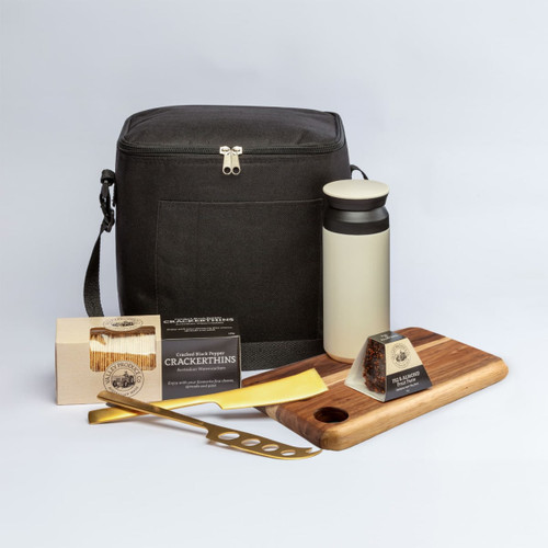 A black cooler bag with a drink bottle, wooden serving board, cheese knife, and packaged snacks. Contains a logo.