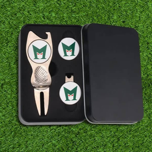 A silver golf divot tool and two ball markers in a black gift box, placed on green grass.