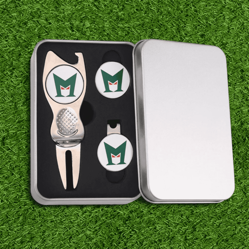 A silver gift box containing a metal golf divot tool and two golf ball markers with a logo. The background is green grass.