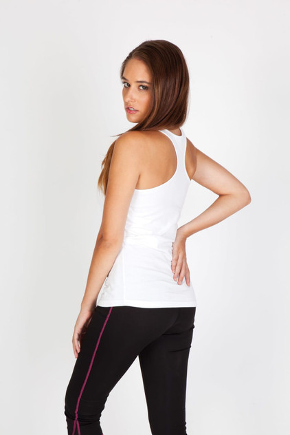 A white women's T-back singlet is displayed, featuring a fitted design and a model wearing it with black pants.