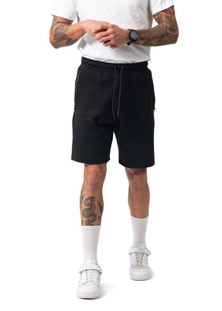 Men's cotton sandwich shorts in black, featuring side pockets and a drawstring waistband, worn with white socks and sneakers.