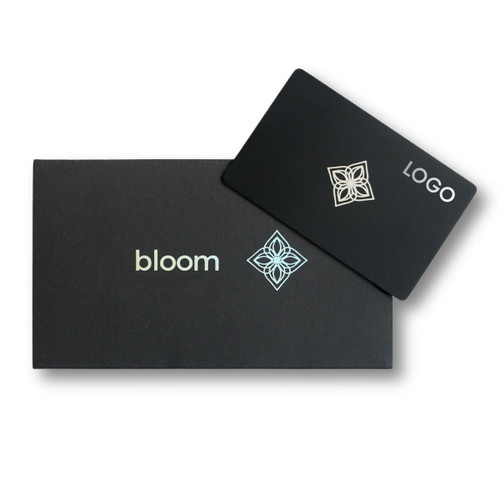 A black packaging box with a silver logo and a card featuring a design and the word "bloom."