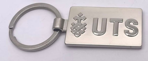 A silver keyring featuring a rectangular shape with a logo and the letters "UTS."