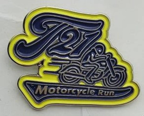 A soft enamel lapel pin featuring a motorcycle design in blue and yellow with a logo. No epoxy finish.