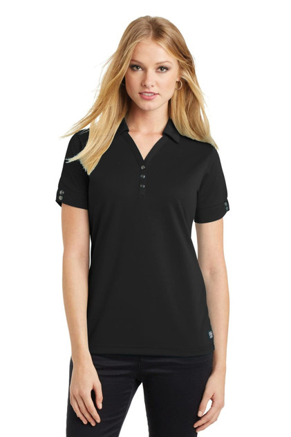 A black OGIO Glam Polo shirt displayed on a model, featuring a collar and short sleeves. The shirt has a logo.