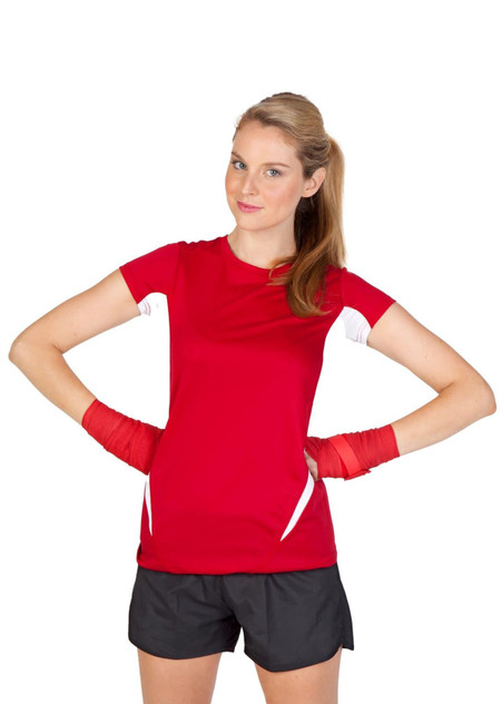 A woman in a red and white short-sleeved T-shirt flexes her arms, wearing black shorts and red hand wraps.