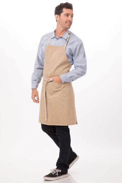 A beige bib apron worn by a man, featuring a pocket and adjustable straps, against a light background.