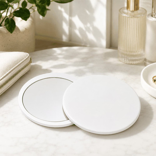 A round, white Glider slider makeup mirror with a sleek design, displayed on a marble surface with accessories.