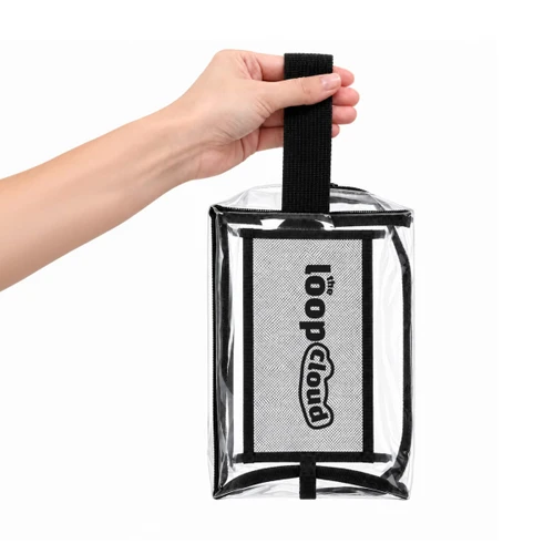 A clear cosmetic bag with a black handle and a branded logo, held by a hand.