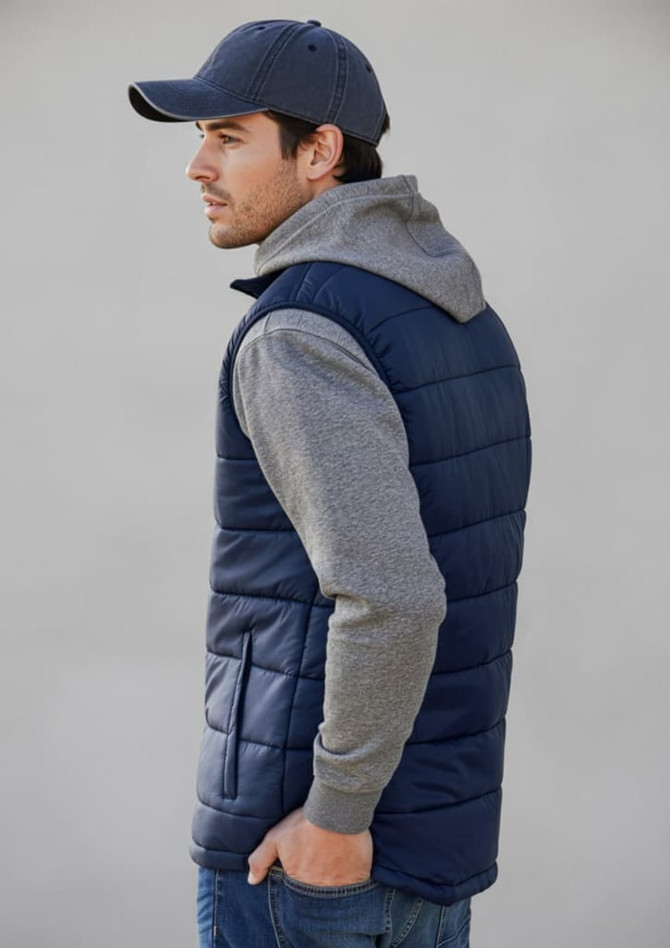 A navy men's alpine vest with grey hooded sleeves, featured on a model facing sideways. The vest has a logo.