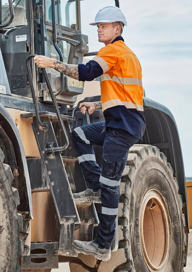 Men's rugged work pants in navy and orange, featuring reflective tape and a logo, worn by a worker climbing machinery.