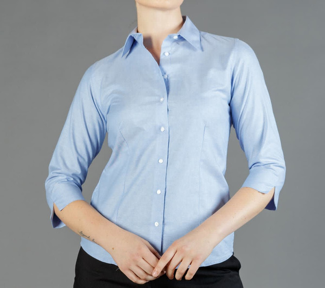 A light blue button-up shirt with three-quarter sleeves and a fitted shape. The shirt has a logo on it.