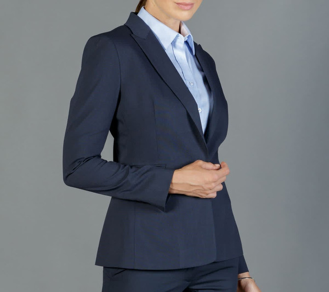 A fitted navy blazer with a structured silhouette, paired with a light blue shirt, featuring a branding logo.