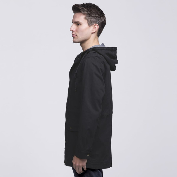 A black twill jacket featuring a hood, displayed on a model from the side, with a logo visible on the garment. A black twill jacket featuring a hood, displayed on a model from the side, with a logo visible on the garment.