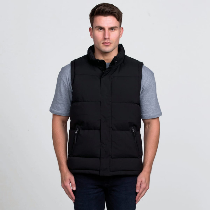 A black puffa vest is worn over a grey short-sleeve shirt, featuring a high collar and side zip pockets.