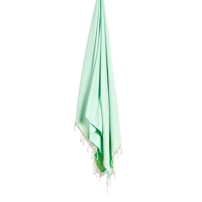 A mint green beach towel with decorative tassels hanging from a hook. It features a smooth texture and a minimalist design. A mint green beach towel with decorative tassels hanging from a hook. It features a smooth texture and a minimalist design.