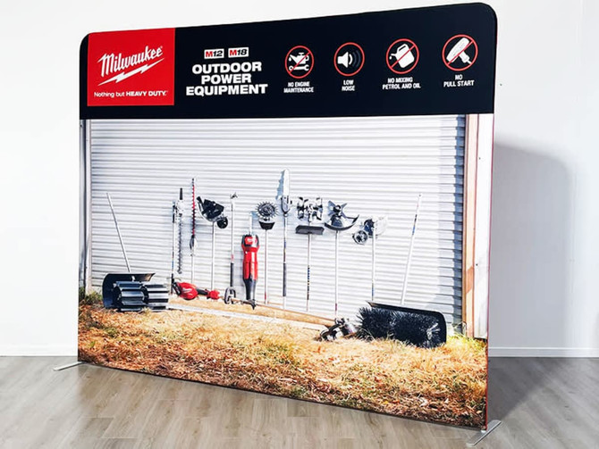 A straight tube fabric stand featuring tools and equipment against a grey wall backdrop. The stand includes a logo.