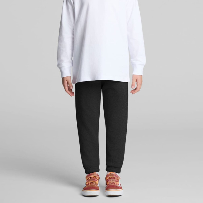 Track pants in dark grey, paired with a long-sleeve white top and red-orange shoes, featuring a logo.