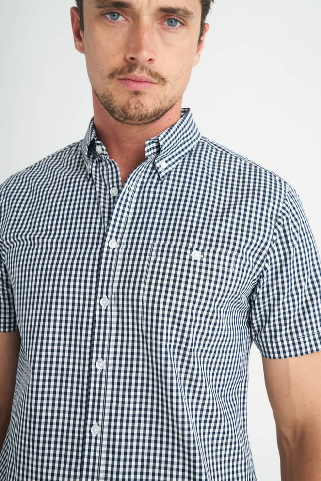 A short-sleeved button-up shirt featuring a black and white check pattern, with a collar and a logo.