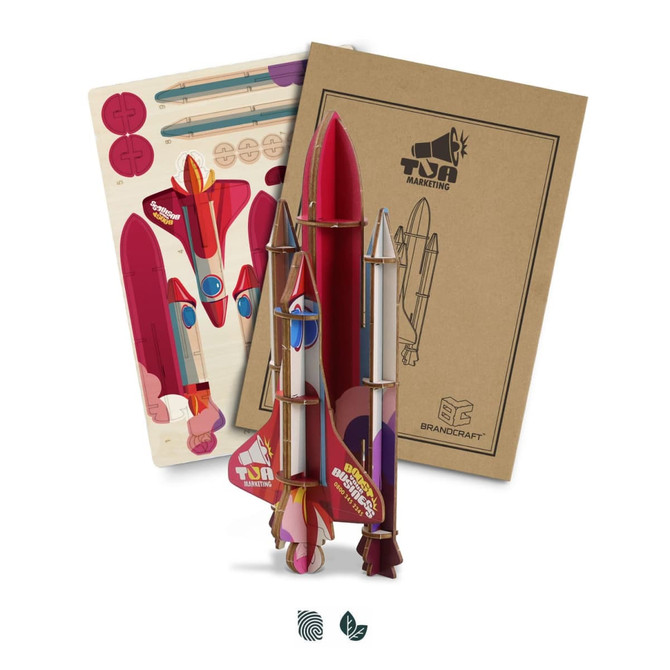 A colourful wooden model rocket kit in shades of red and pink, accompanied by assembly instructions and printed parts.