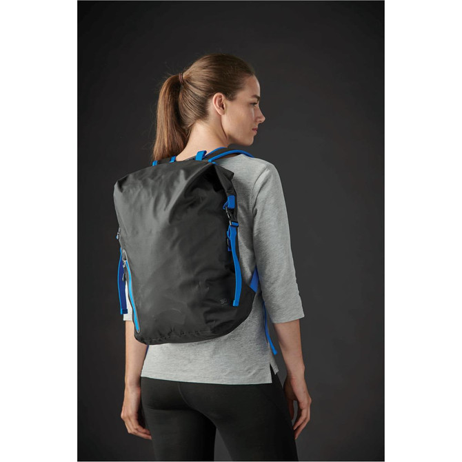 A black backpack with blue accents is worn on the back of a woman in a grey top, set against a dark background.
