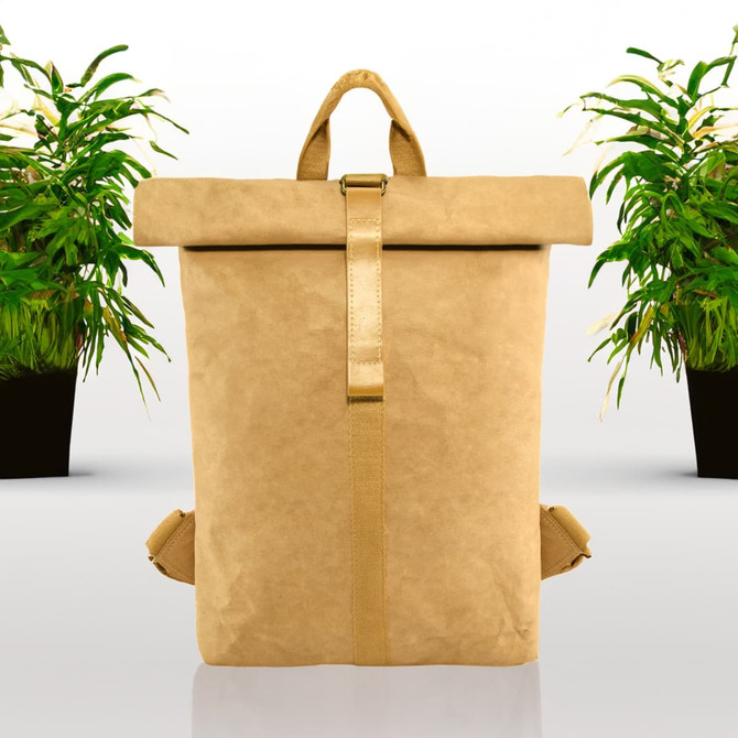 A tan kraft paper backpack with a roll-top closure and adjustable straps, surrounded by potted plants.