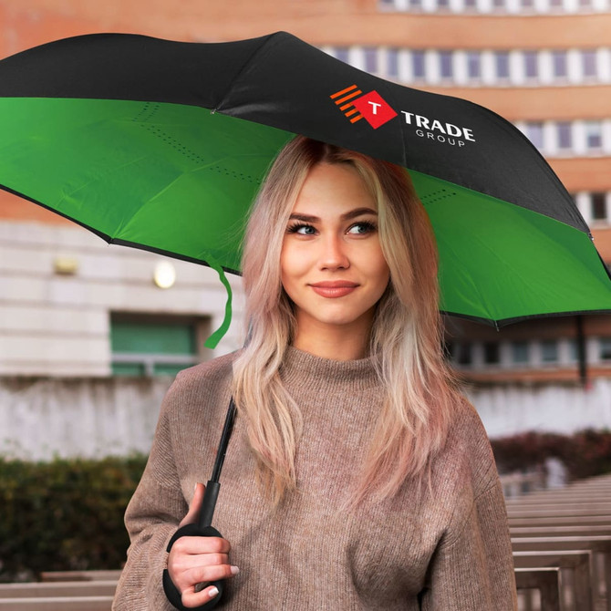 An inverted umbrella with a black exterior and green interior, held by a person with long blonde hair. It features a logo.