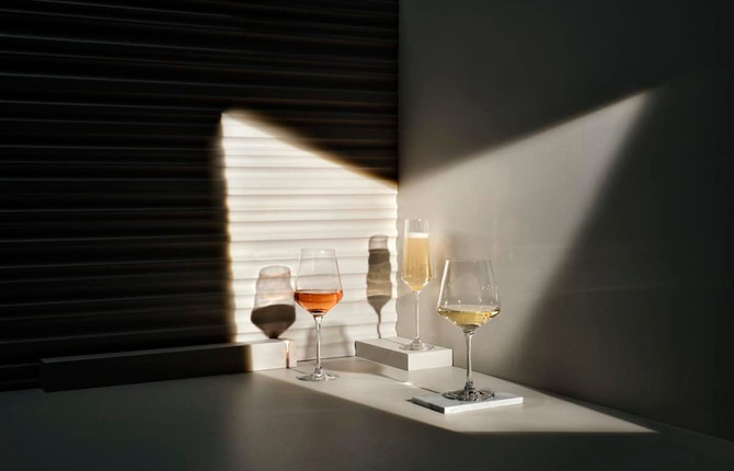 Three elegant wine glasses featuring rose, white, and sparkling wine, casting shadows in soft lighting.