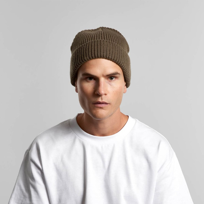 A beanie in a muted brown colour, worn by a model, featuring ribbed texture and a logo.