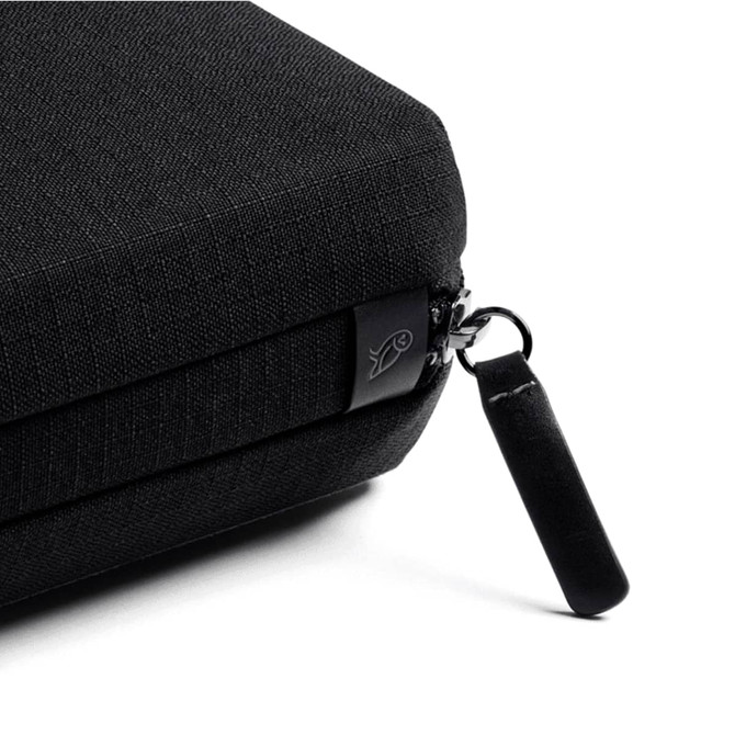 A black tech kit with a textured surface and a zip closure featuring a small black pull tab.